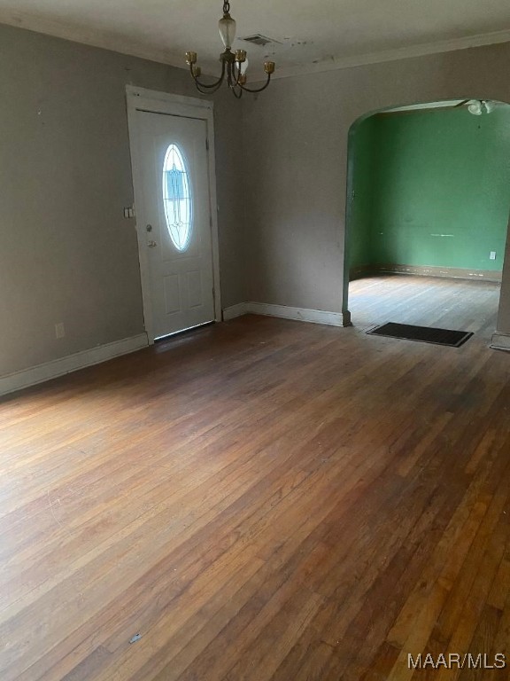 entryway featuring hardwood / wood-style flooring, an inviting chandelier, and ornamental molding