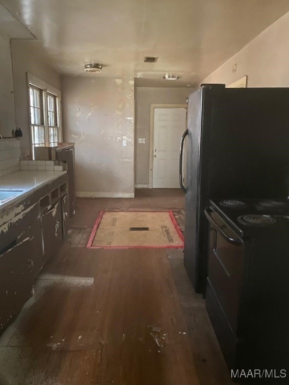 kitchen featuring backsplash, dark hardwood / wood-style flooring, and black range oven