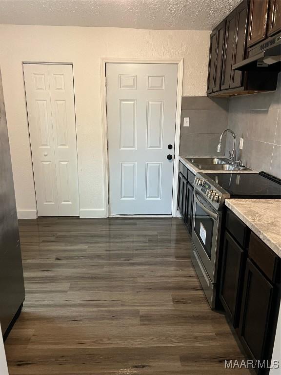 kitchen featuring dark brown cabinetry, extractor fan, sink, dark hardwood / wood-style floors, and stainless steel range with electric cooktop