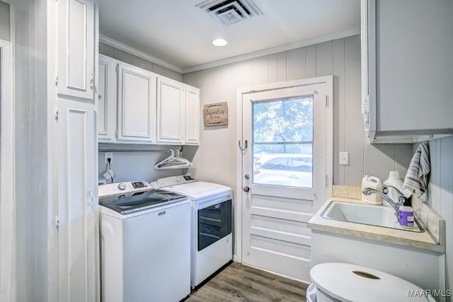 laundry room featuring sink, dark wood-type flooring, cabinets, washer and clothes dryer, and ornamental molding