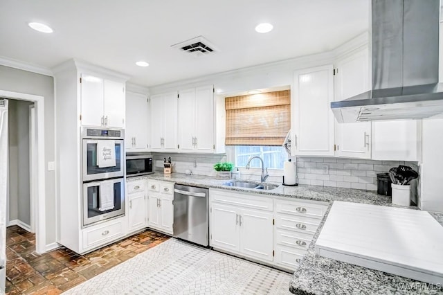 kitchen with sink, stainless steel appliances, wall chimney range hood, tasteful backsplash, and white cabinets