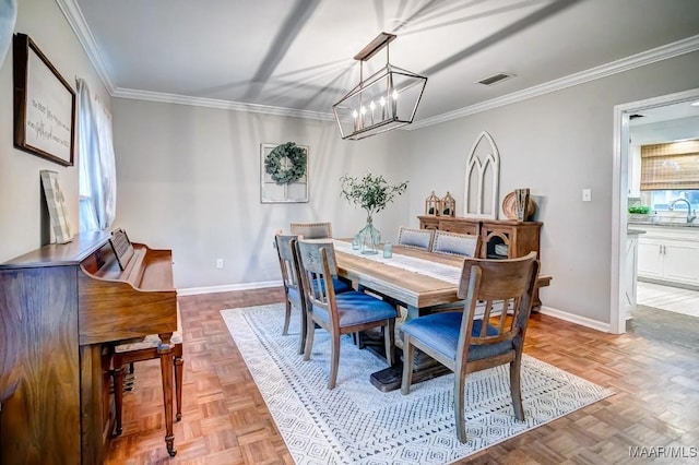 dining space featuring sink, light parquet flooring, ornamental molding, and a notable chandelier