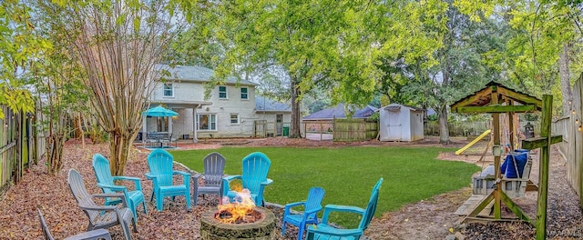 view of yard with a playground, a fire pit, and a storage unit