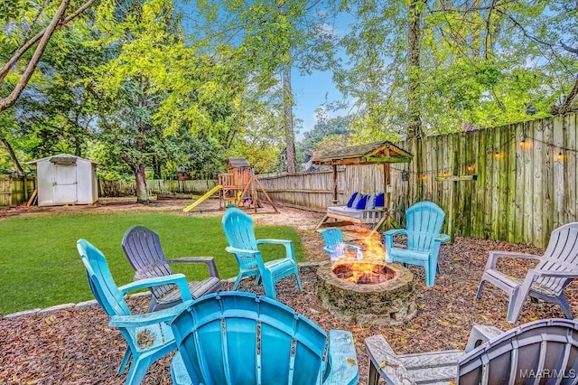 view of yard featuring a playground, a shed, and an outdoor fire pit