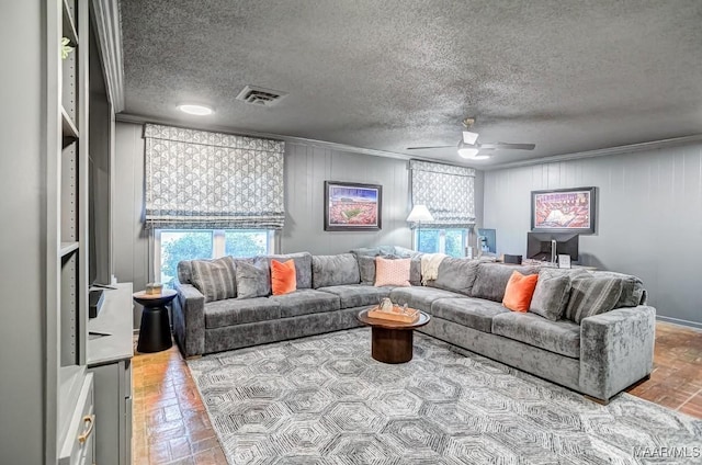 living room featuring a textured ceiling, ceiling fan, and crown molding