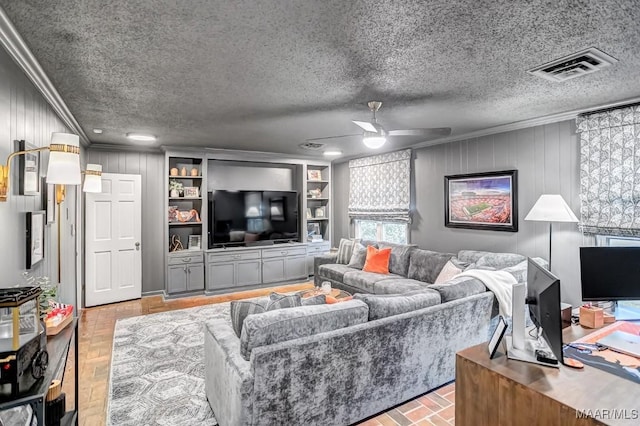 living room with ceiling fan, built in features, ornamental molding, and a textured ceiling