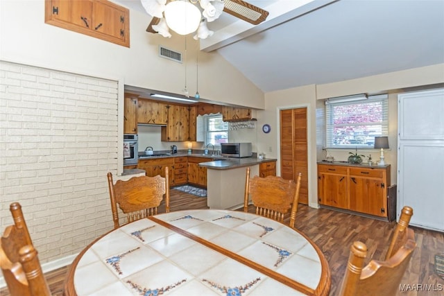 dining room with beamed ceiling, plenty of natural light, ceiling fan, and brick wall