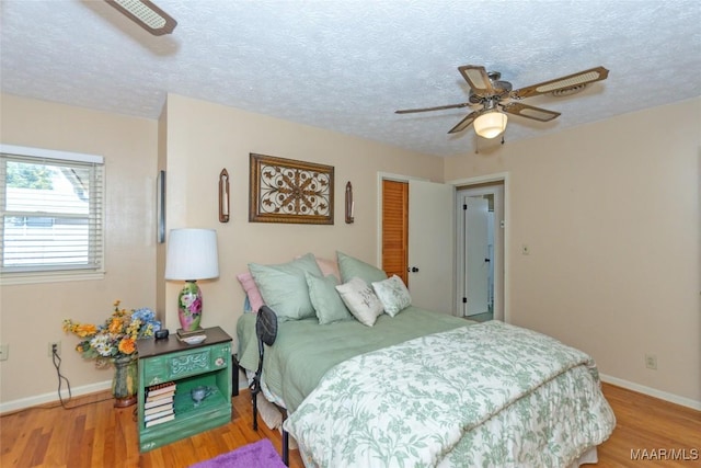 bedroom featuring wood-type flooring, a textured ceiling, a closet, and ceiling fan