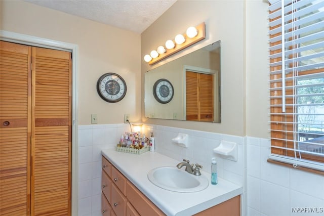 bathroom featuring a textured ceiling, vanity, and tile walls