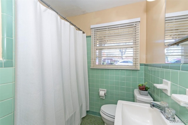 bathroom featuring toilet, sink, walk in shower, and tile walls