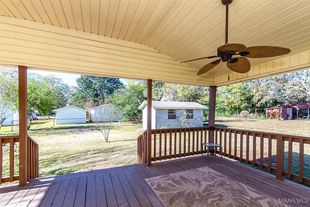 wooden terrace featuring an outbuilding, ceiling fan, and a lawn