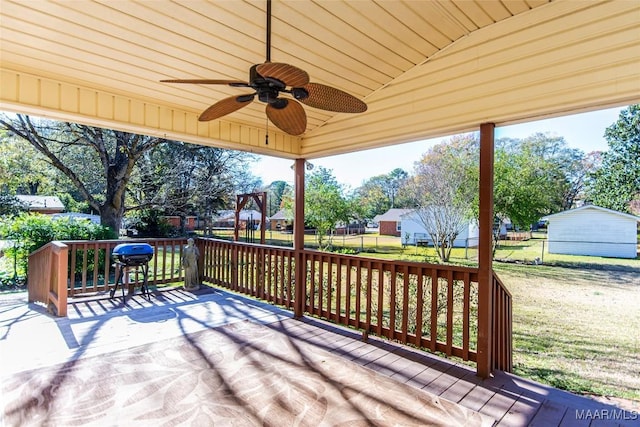 wooden terrace featuring grilling area, ceiling fan, and a lawn