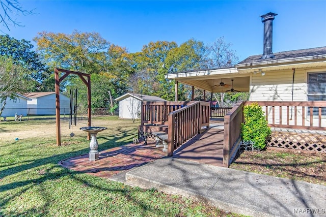 view of yard with a storage shed, ceiling fan, and a deck