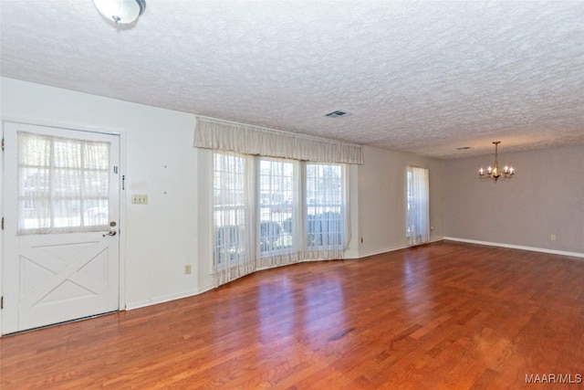 interior space featuring hardwood / wood-style floors, a textured ceiling, and a notable chandelier