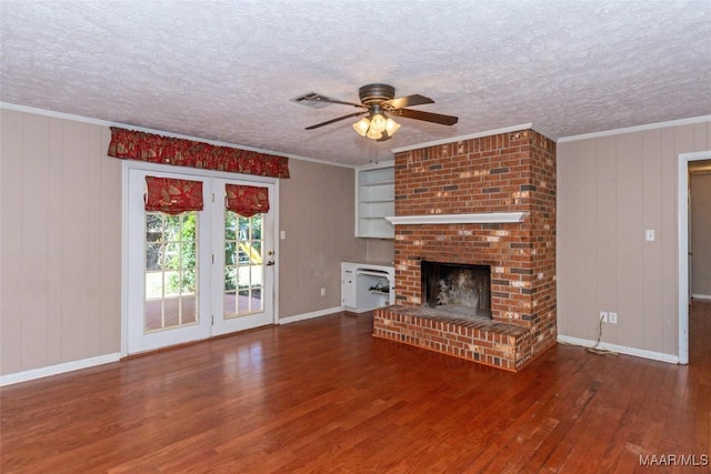 unfurnished living room featuring crown molding, wooden walls, ceiling fan, a fireplace, and wood-type flooring