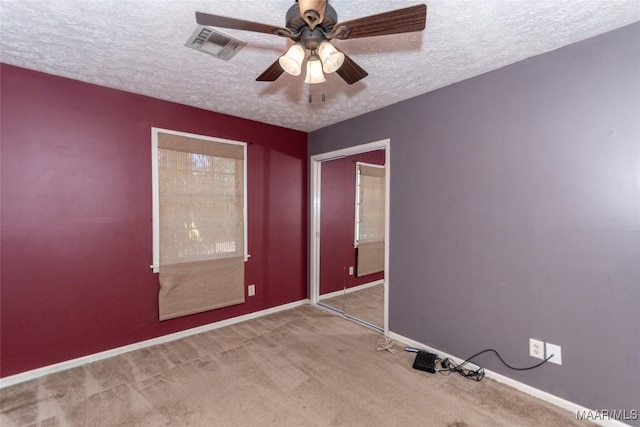 carpeted spare room featuring a textured ceiling and ceiling fan