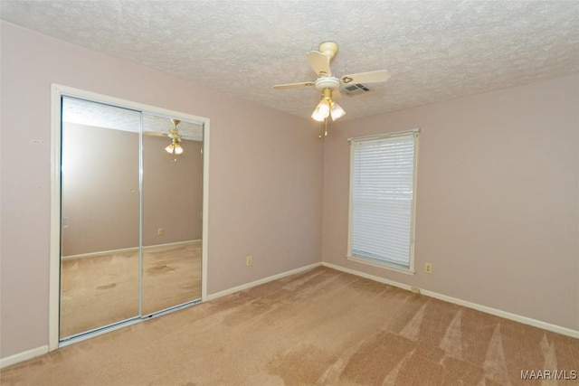 unfurnished bedroom with carpet, a textured ceiling, a closet, and ceiling fan