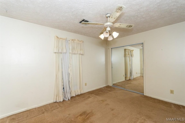 carpeted empty room featuring ceiling fan and a textured ceiling