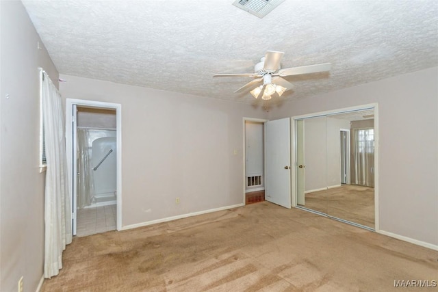 unfurnished bedroom with ensuite bathroom, ceiling fan, light colored carpet, and a textured ceiling