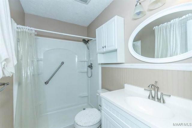 bathroom with a shower with curtain, vanity, a textured ceiling, and toilet