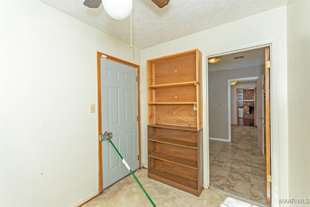 interior space featuring ceiling fan, a textured ceiling, and a brick fireplace