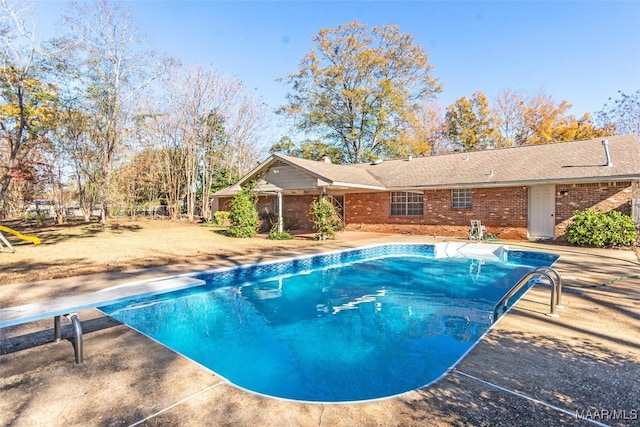 view of pool with a diving board and a patio area