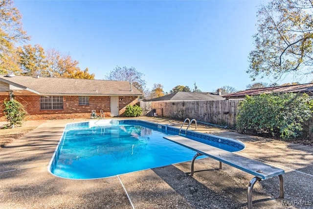 view of swimming pool with a patio area and a diving board