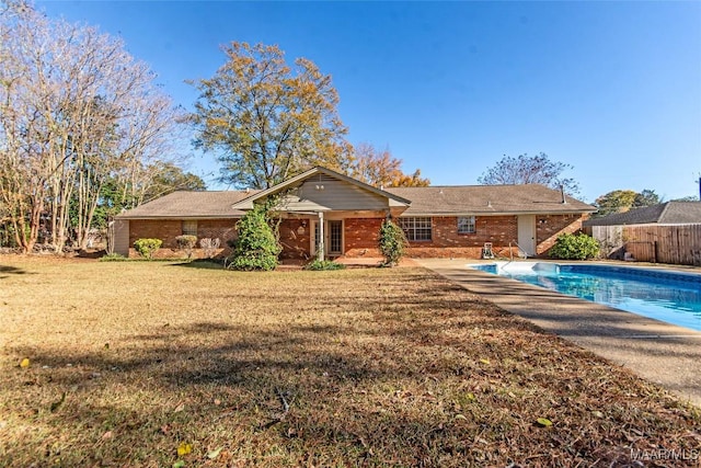 back of property featuring a yard and a fenced in pool