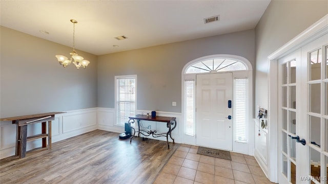 foyer entrance with a notable chandelier, light wood-type flooring, and french doors