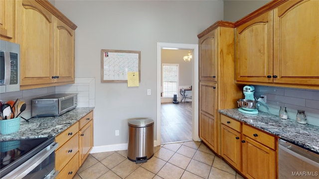 kitchen with stone counters, an inviting chandelier, light tile patterned floors, tasteful backsplash, and stainless steel appliances