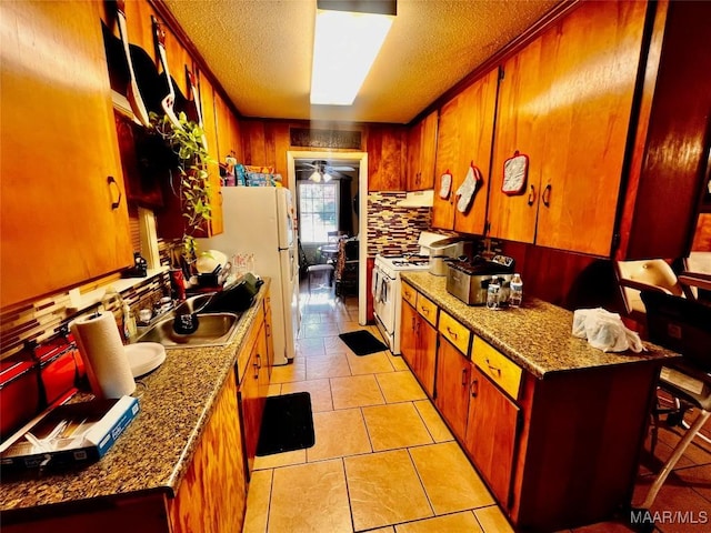 kitchen featuring decorative backsplash, a kitchen breakfast bar, a textured ceiling, white appliances, and stone counters