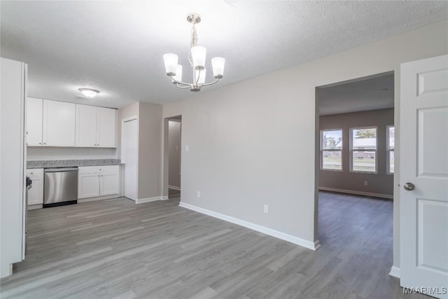 kitchen with an inviting chandelier, stainless steel dishwasher, pendant lighting, white cabinets, and light wood-type flooring