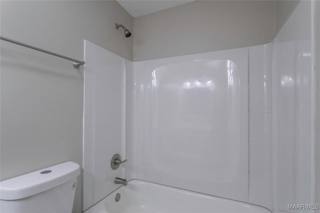 bathroom with a textured ceiling,  shower combination, and toilet