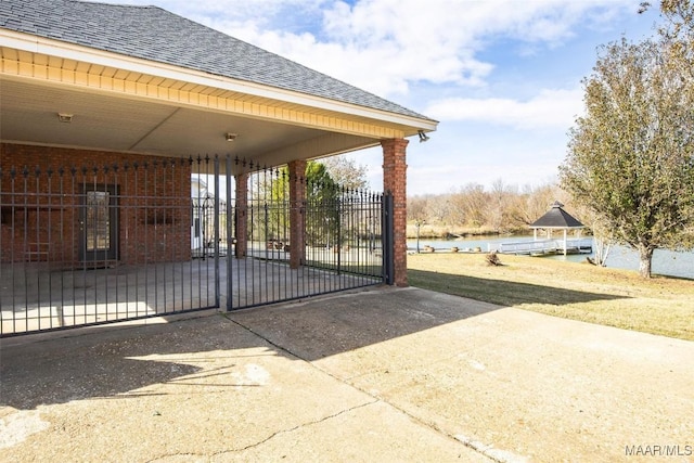 view of gate with a water view and a carport