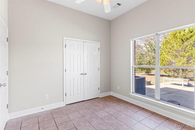 unfurnished bedroom with ceiling fan, light tile patterned floors, and a closet