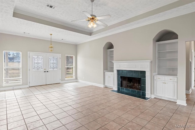 unfurnished living room with built in features, light tile patterned floors, and a textured ceiling