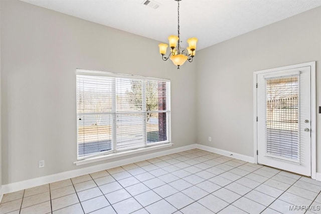 tiled spare room with a healthy amount of sunlight and an inviting chandelier