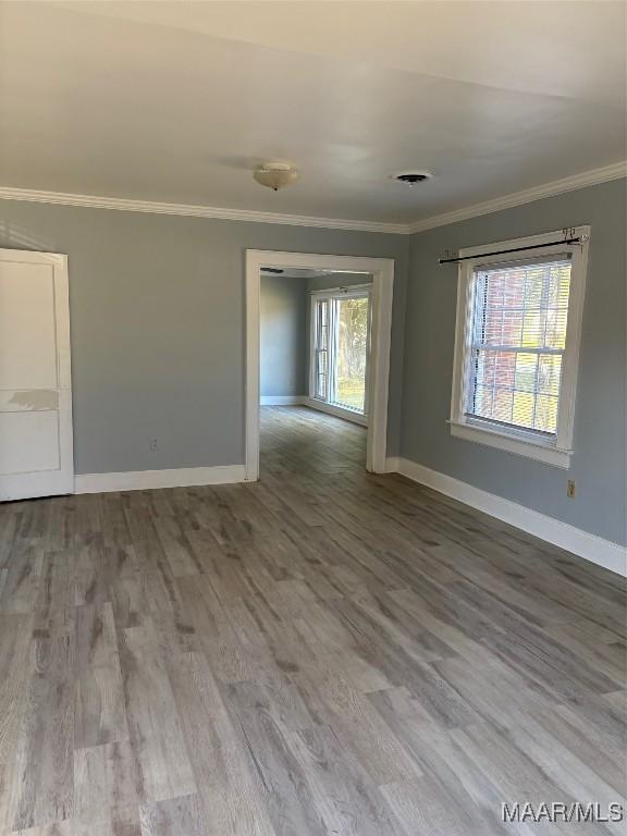 empty room with baseboards, ornamental molding, and wood finished floors