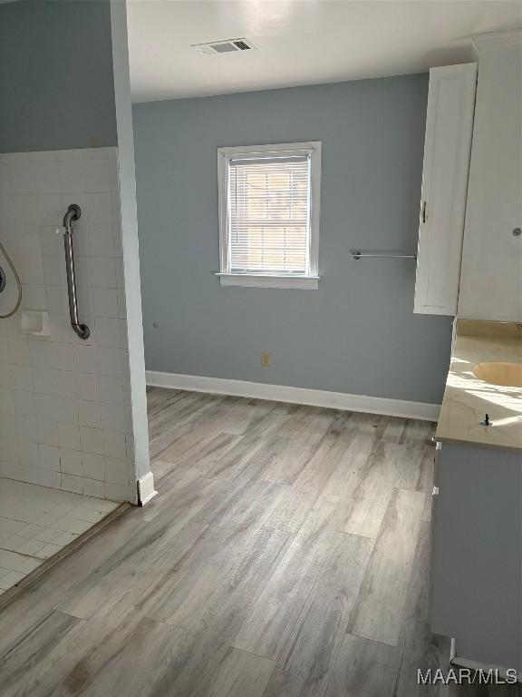 full bathroom featuring wood finished floors, visible vents, and tiled shower