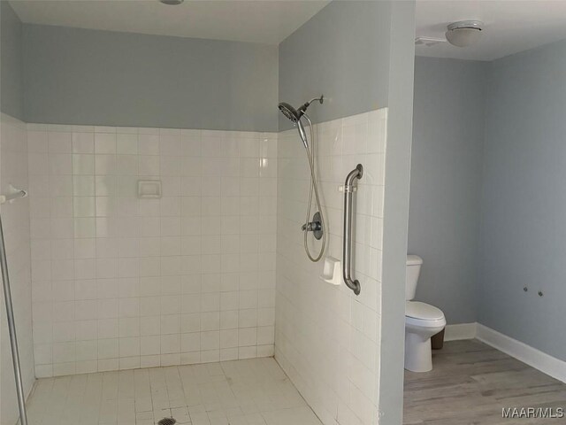 full bath featuring tiled shower, wood finished floors, and toilet
