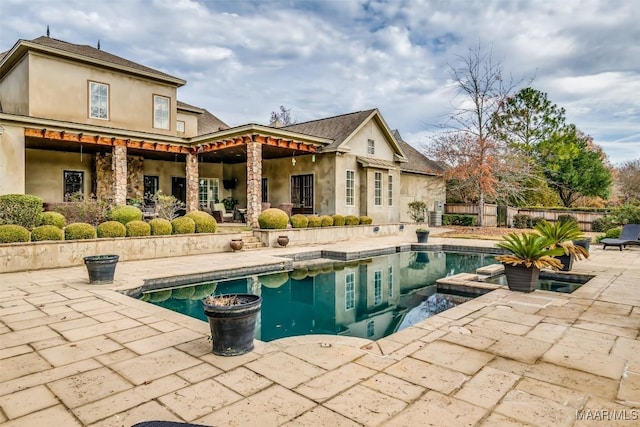 rear view of house featuring a fenced in pool and a patio area