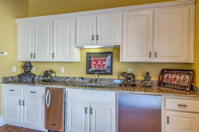 kitchen featuring white cabinets, stainless steel refrigerator, stone counters, and sink