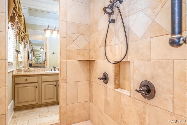 bathroom featuring a tile shower, crown molding, and vanity