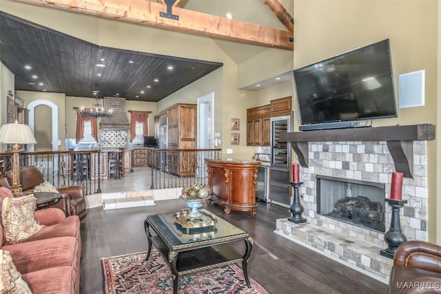 living room with beam ceiling, a stone fireplace, hardwood / wood-style floors, and high vaulted ceiling