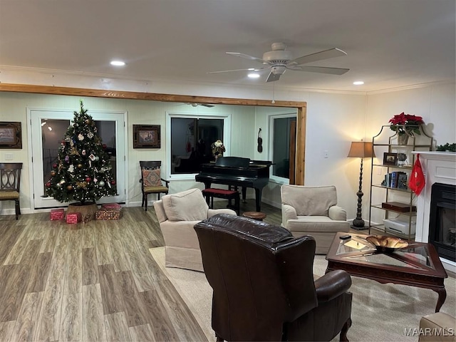 living room with ceiling fan, wood-type flooring, and ornamental molding