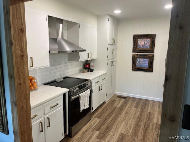 kitchen featuring white cabinets, stainless steel range with electric cooktop, and wall chimney exhaust hood