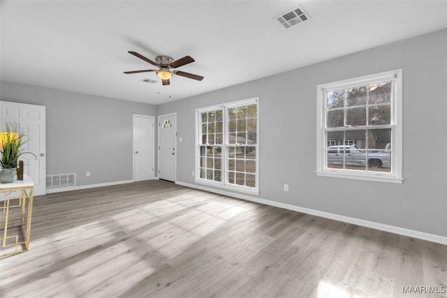 empty room with ceiling fan and light hardwood / wood-style floors