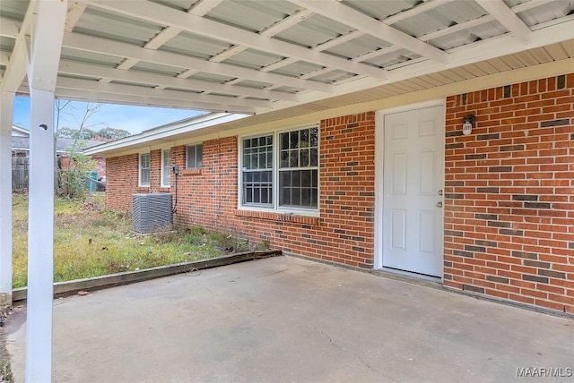 view of exterior entry with central AC unit and a patio