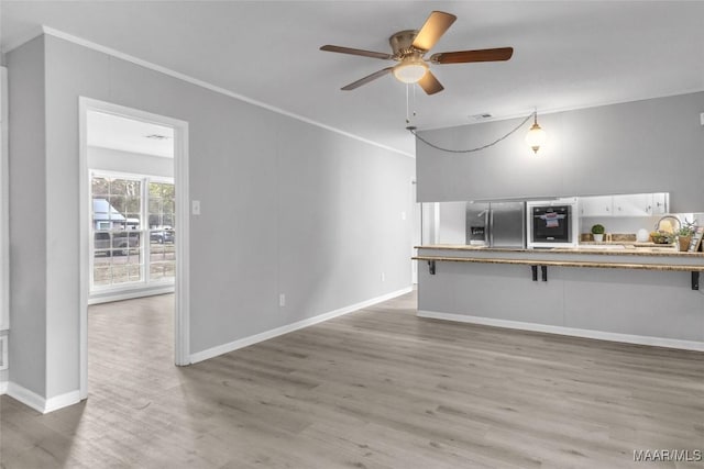 unfurnished living room with ceiling fan, light wood-type flooring, and crown molding