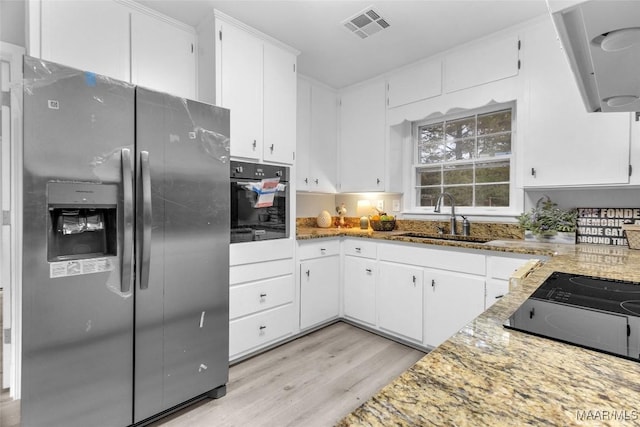 kitchen featuring white cabinetry, sink, black appliances, and light wood-type flooring